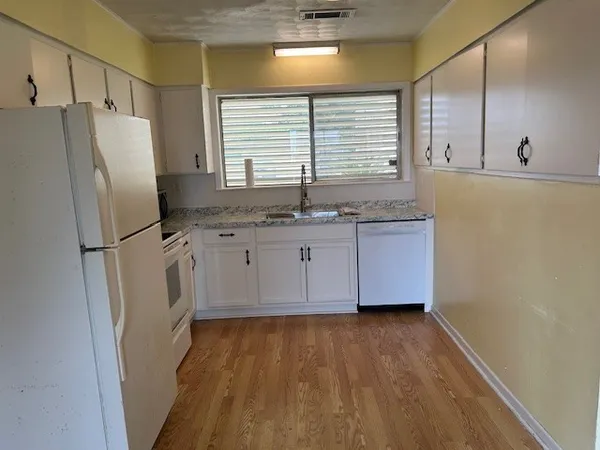 a kitchen with granite countertop a refrigerator a sink and dishwasher