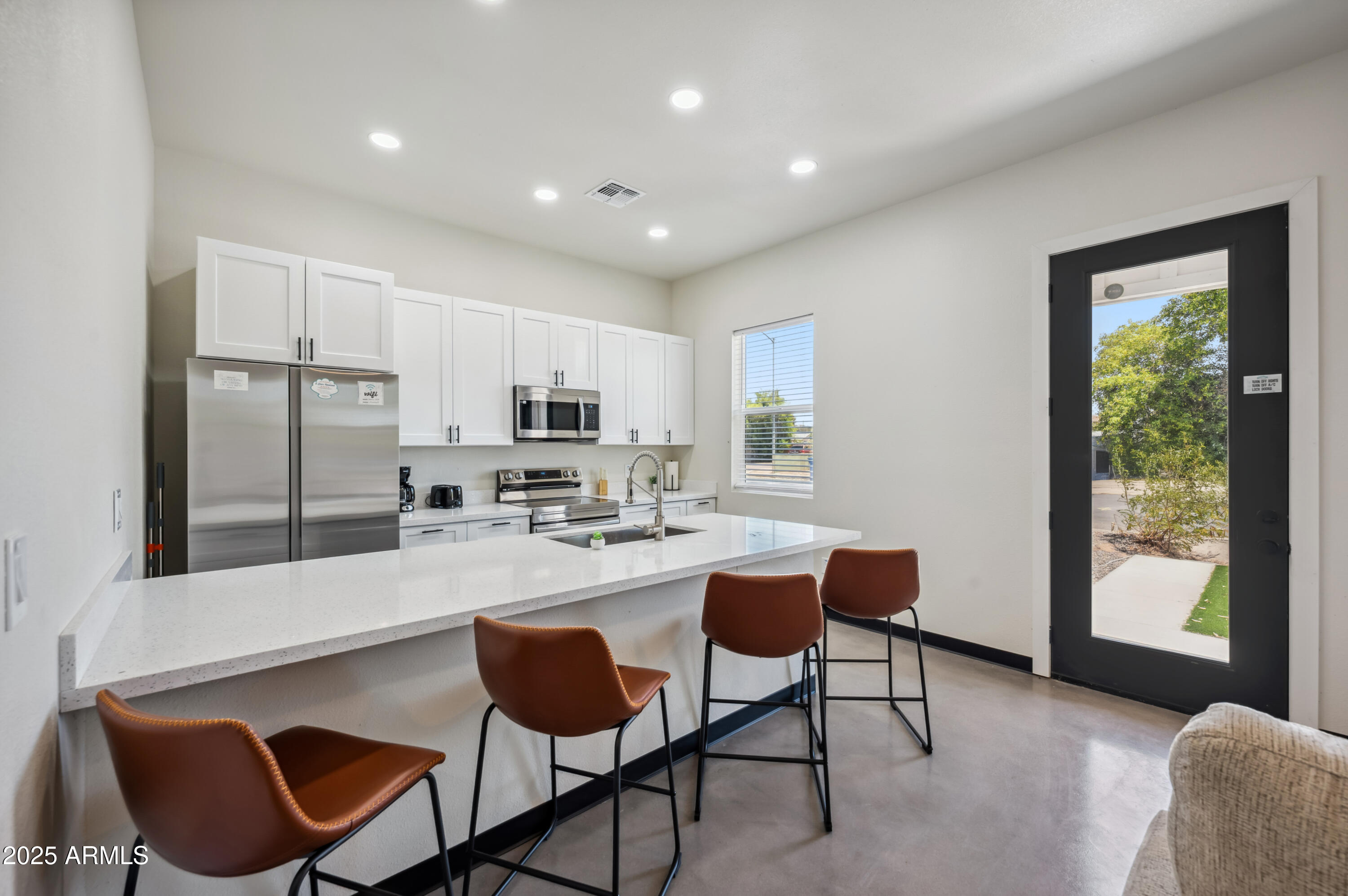 a kitchen with stainless steel appliances granite countertop a table chairs and a refrigerator