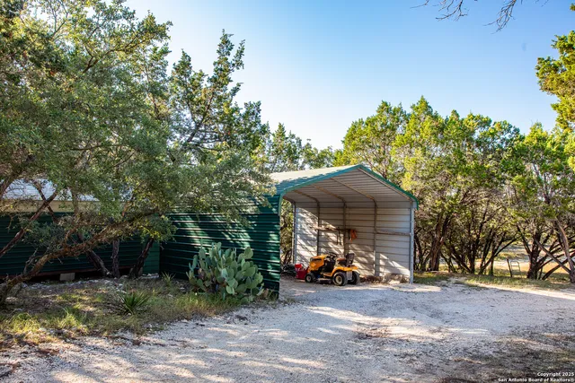 a view of a wooden house with large trees and playing area