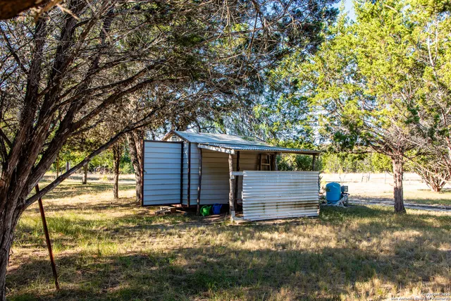 a view of a house that has wooden fence and a tree