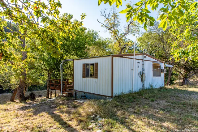a view of a house with large tree and wooden fence