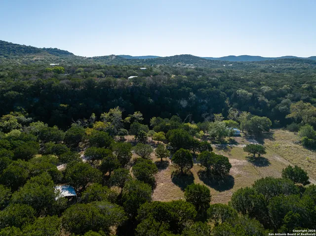 an aerial view of a houses with a lush green hillside