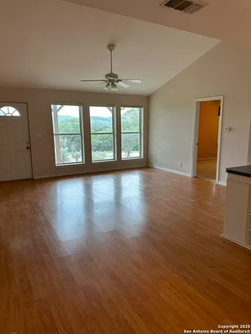 a view of an empty room with wooden floor and a window