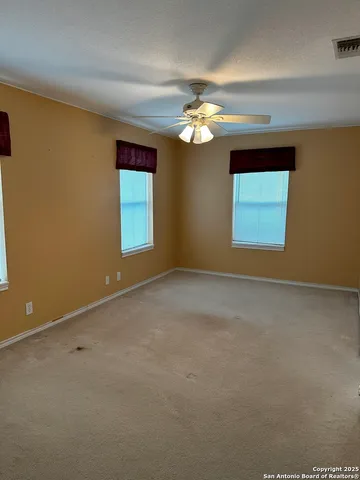 an empty room with windows and chandelier fan