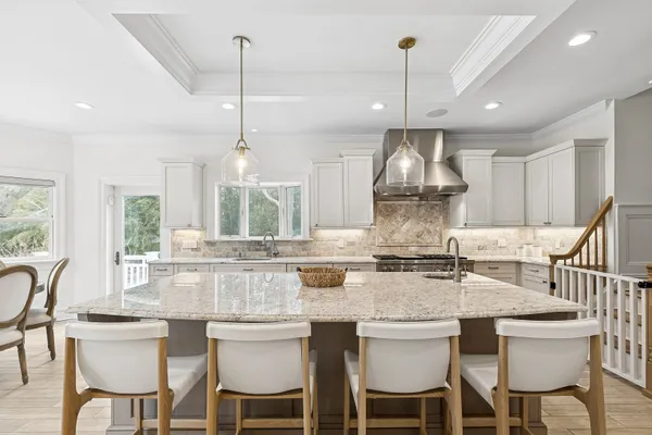 a kitchen with stainless steel appliances granite countertop a dining table chairs and white cabinets