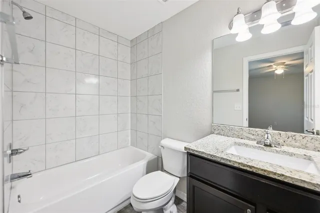 a bathroom with a granite countertop bathtub sink vanity mirror and toilet