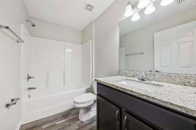 a bathroom with a granite countertop sink a toilet a mirror and bathtub