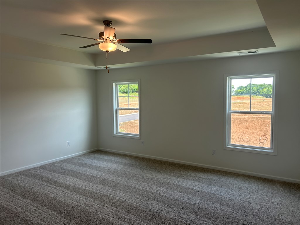 217 Bellflower Lane Anderson, SC 29625 - Photo 16 of 27 A spacious, naturally illuminated room boasts plush carpeting and a modern tray ceiling with an integrated ceiling fan.