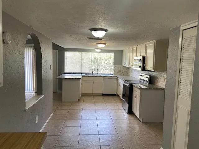 a kitchen with a sink a counter top space cabinets and appliances