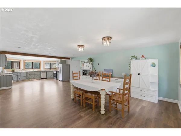 a kitchen with stainless steel appliances granite countertop a stove top oven a sink dishwasher a dining table and chairs with wooden floor