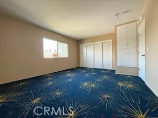 a view of an empty room with window and closet area