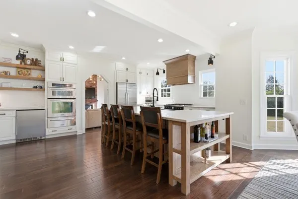 a kitchen with stainless steel appliances kitchen island granite countertop a table chairs sink and cabinets