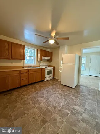 a kitchen with granite countertop a sink a stove a refrigerator a microwave a counter top cabinets and a window