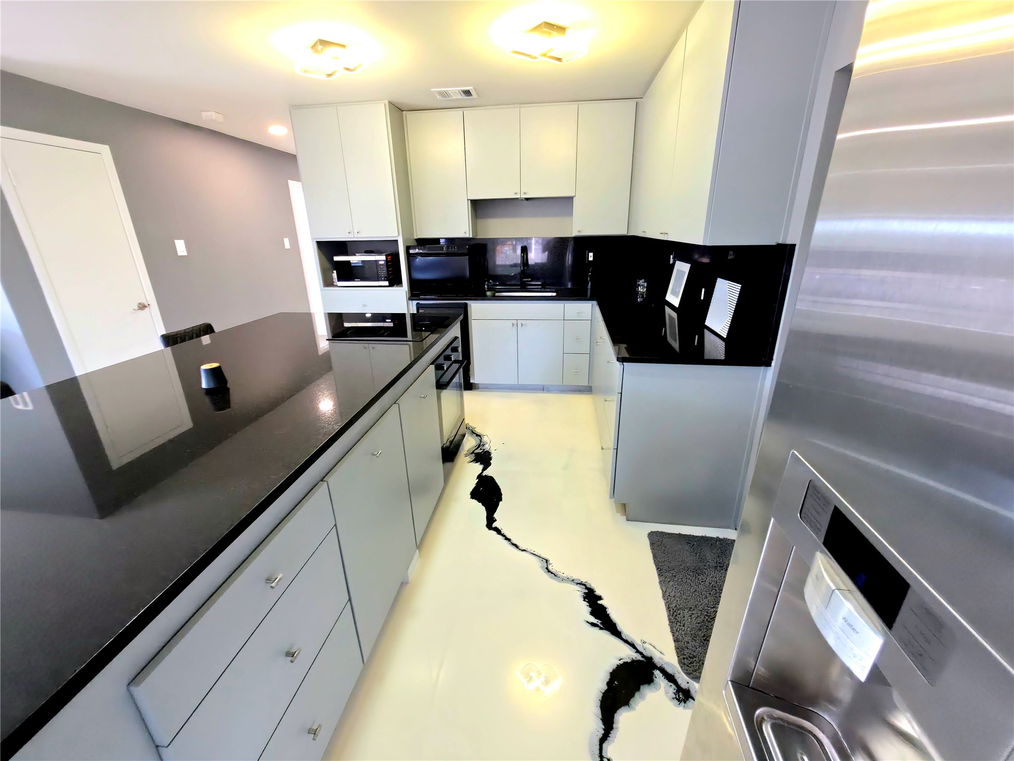 High-contrast stone counters pair with unique epoxy flooring in this modern kitchen space.