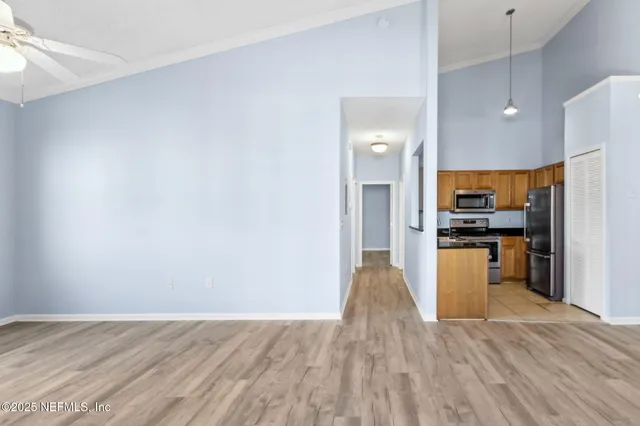 a view of kitchen with kitchen island wooden floor stainless steel appliances and cabinets