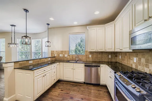 a kitchen with stainless steel appliances a sink a stove and cabinets
