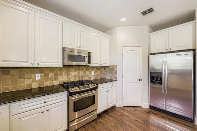 a kitchen with white cabinets and stainless steel appliances