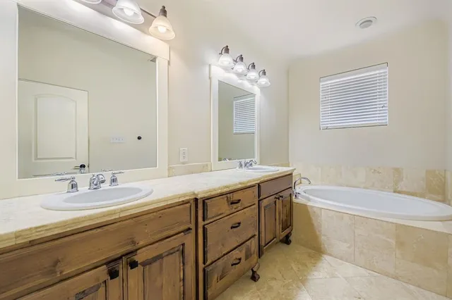 a spacious bathroom with a double vanity sink large mirror and a bathtub
