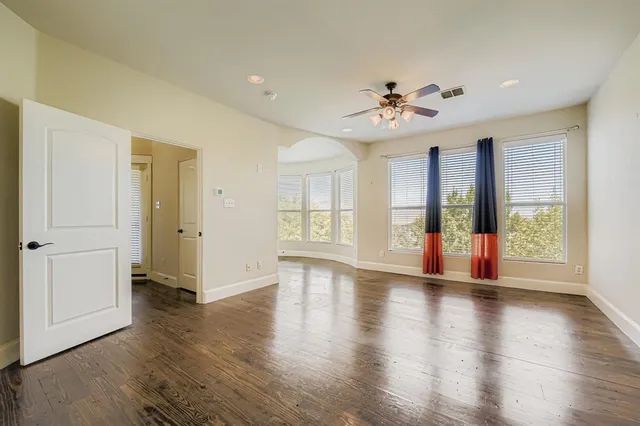 a view of an empty room with window and wooden floor