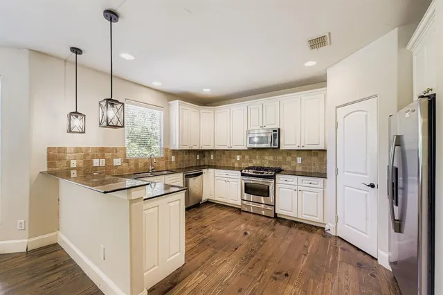 a kitchen with a refrigerator a sink and wooden floor