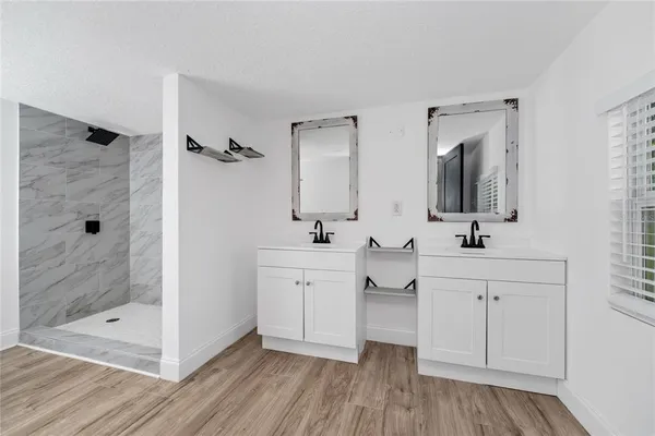 a bathroom with a double vanity sink mirror and shower