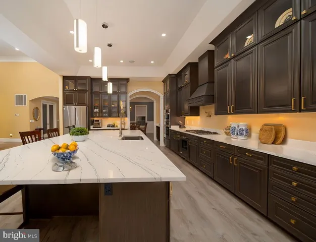 a large kitchen with stainless steel appliances a large counter top a stove a sink dishwasher and cabinets with wooden floor