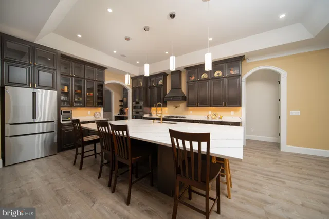 a kitchen with stainless steel appliances kitchen island granite countertop a table chairs and a refrigerator