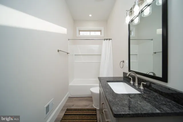 a bathroom with a granite countertop sink a mirror and shower
