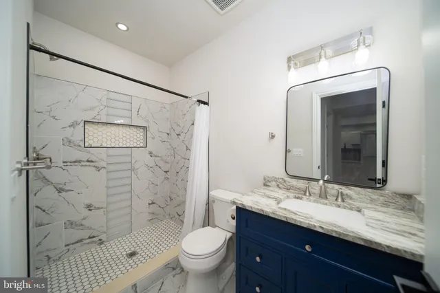 a bathroom with a granite countertop sink toilet and shower