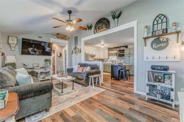 a living room with furniture a flat screen tv and kitchen view