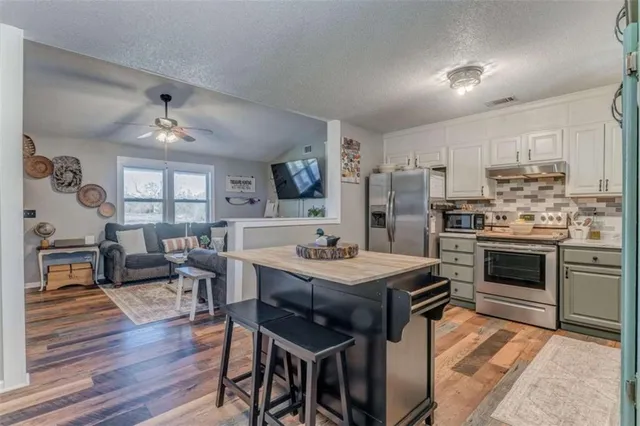 a kitchen with a stove a refrigerator and a dining table with wooden floor