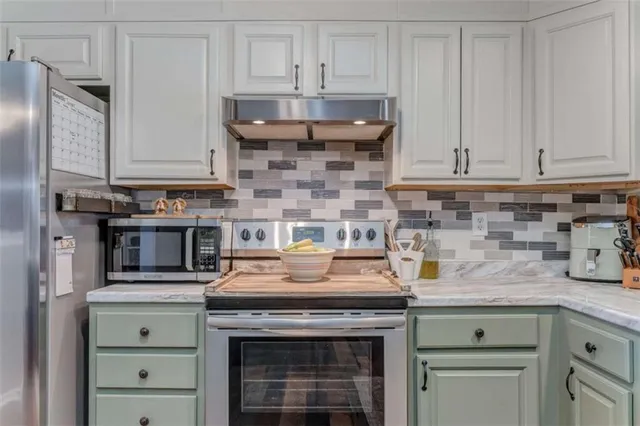 a kitchen with stainless steel appliances granite countertop a stove and a white cabinets