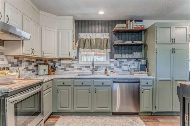 a kitchen with stainless steel appliances granite countertop a sink a stove and cabinets
