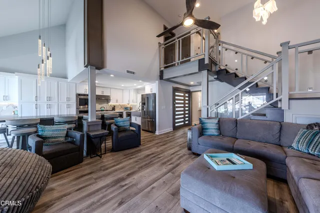 a living room with furniture kitchen view and a wooden floor