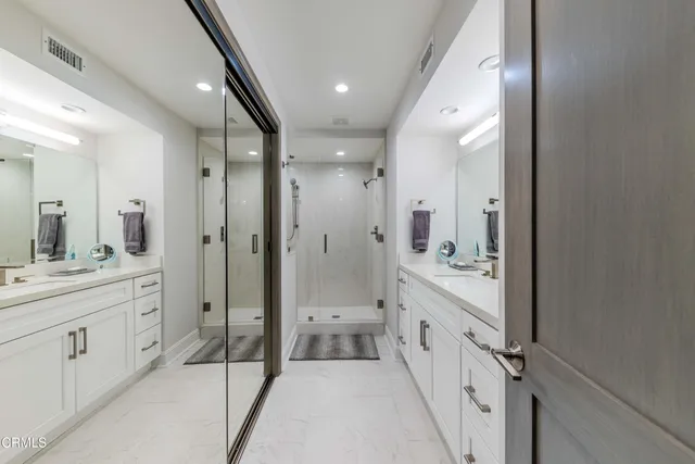 a bathroom with a double vanity sink a toilet a mirror and shower