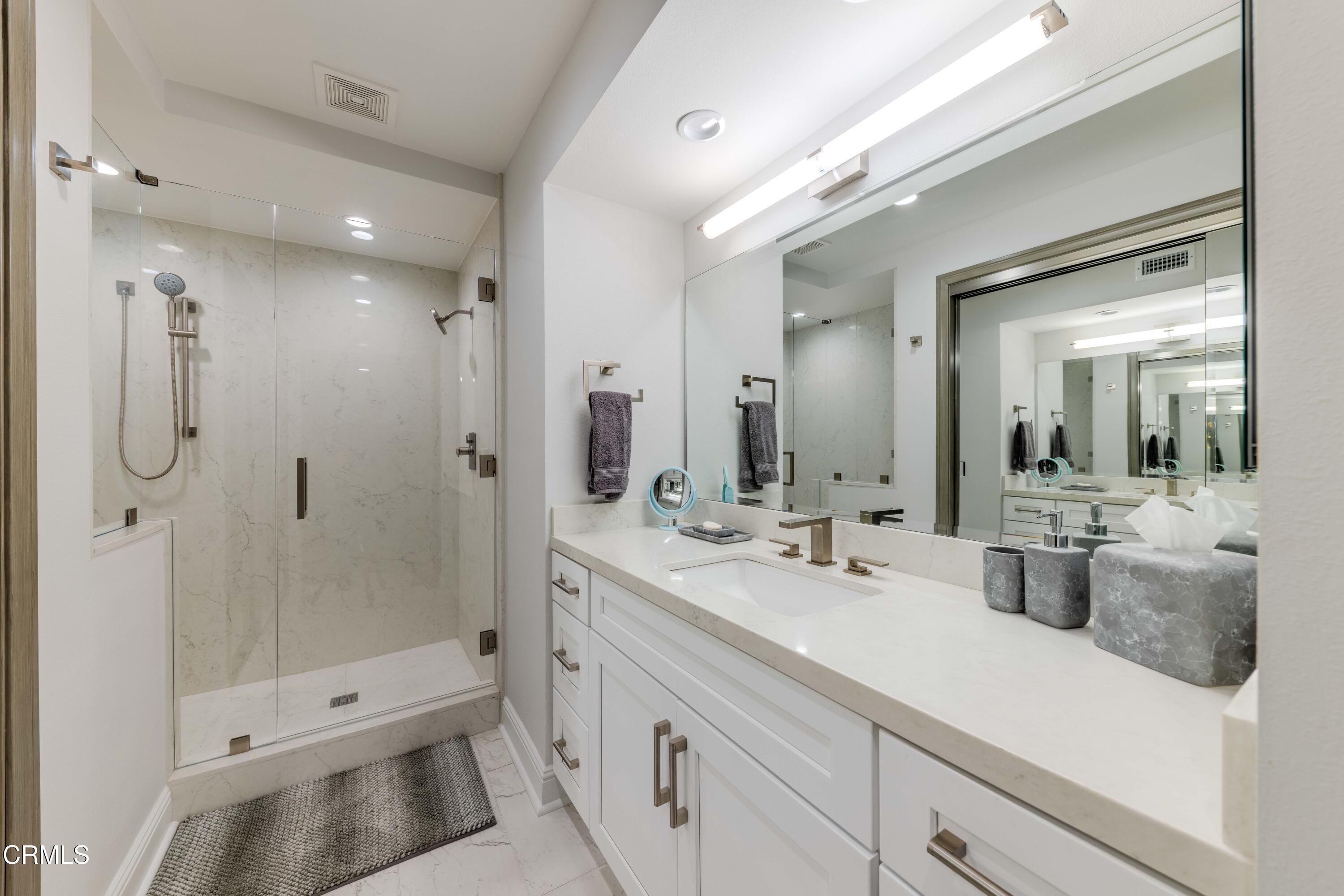 4511 Gateshead Bay Oxnard, CA 93035 - Photo 24 of 36 a bathroom with a double vanity sink toilet mirror and shower