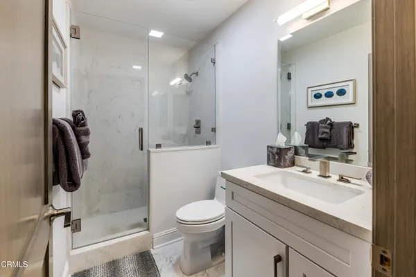 a bathroom with a sink a toilet a mirror and shower