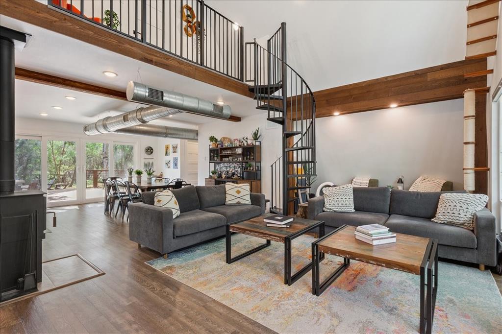15988 Wortham Bend Road China Spring, TX 76633 - Photo 6 of 40 Spacious living area featuring a prominent spiral staircase, wood-finish flooring, exposed wood beams, and a black wood-burning stove