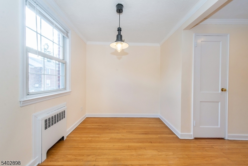 445 Morris Avenue, Unit 7 Springfield, NJ 07081 - Photo 6 of 16 a view of an empty room with wooden floor and a window