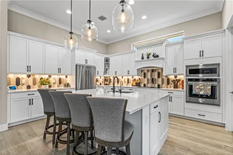 a kitchen with stainless steel appliances granite countertop a dining table chairs refrigerator and sink