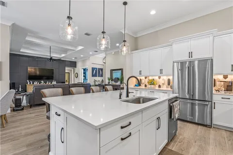a kitchen with stainless steel appliances kitchen island granite countertop a table chairs sink and cabinets