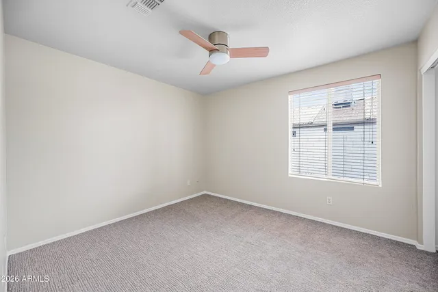 an empty room with a ceiling fan and windows