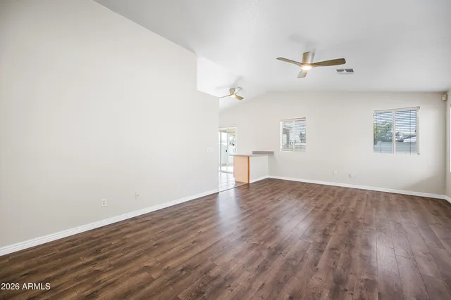 an empty room with wooden floor fan and windows