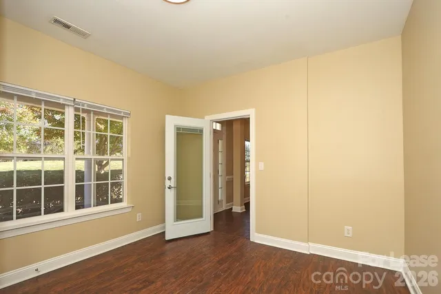 an empty room with wooden floor and windows