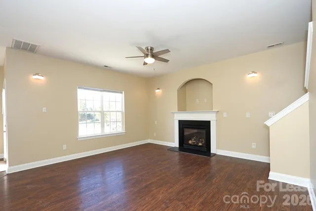 an empty room with windows fireplace and wooden floor