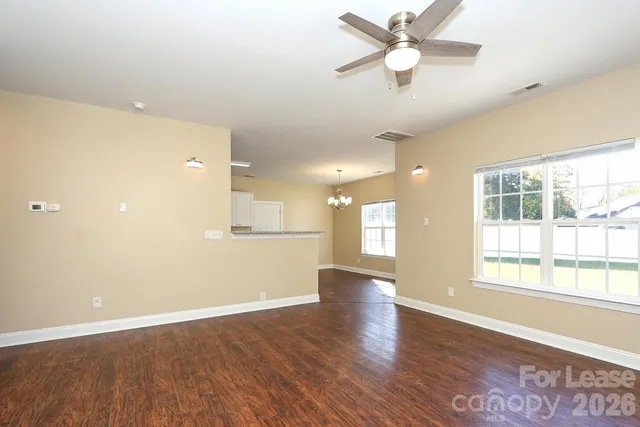 a view of an empty room with window and wooden floor