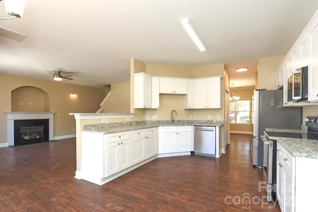 a large kitchen with granite countertop a stove top oven a sink a counter space and cabinets