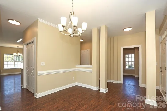 a view of a hallway with wooden floor and chandelier