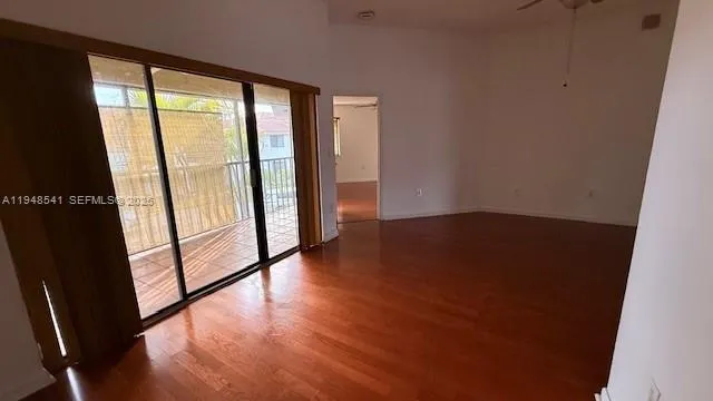 a view of an empty room with wooden floor and a window