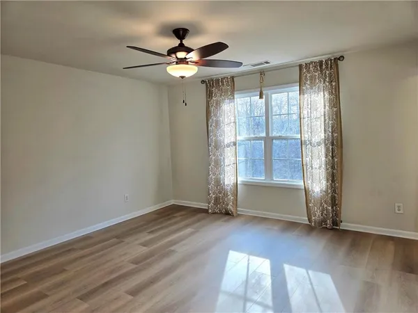 an empty room with wooden floor and windows